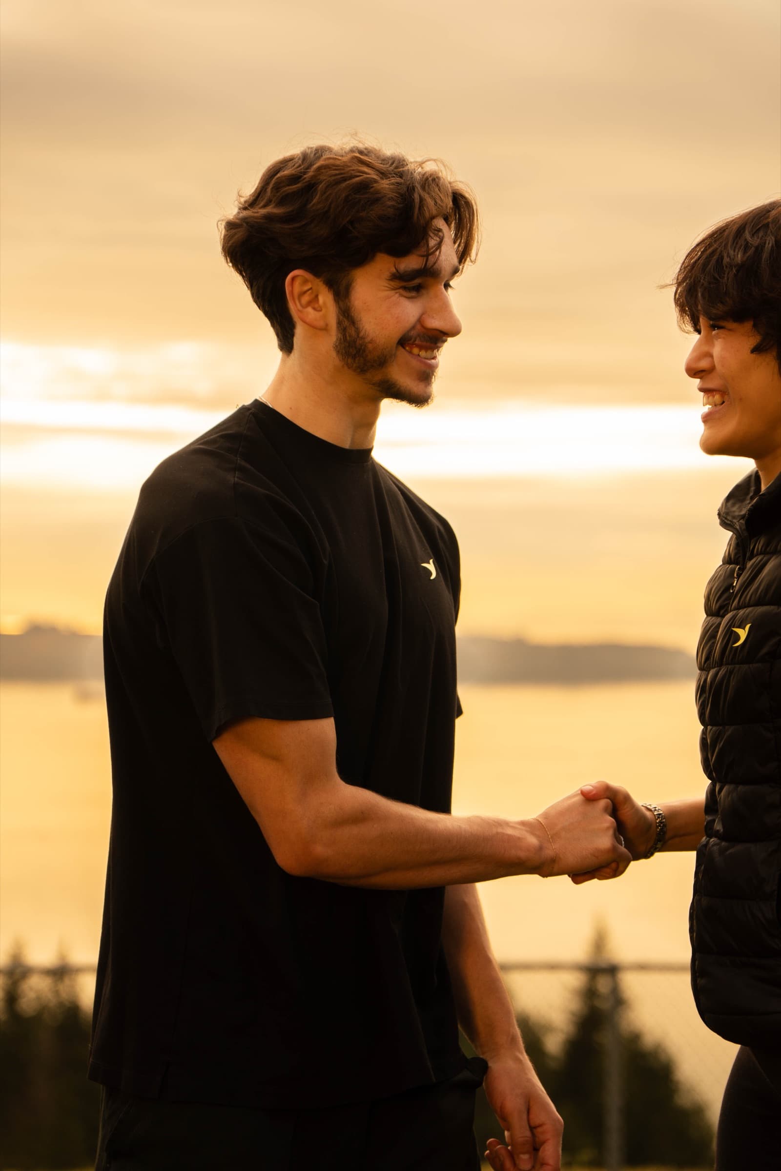 A coach greeting a client with a handshake at sunset